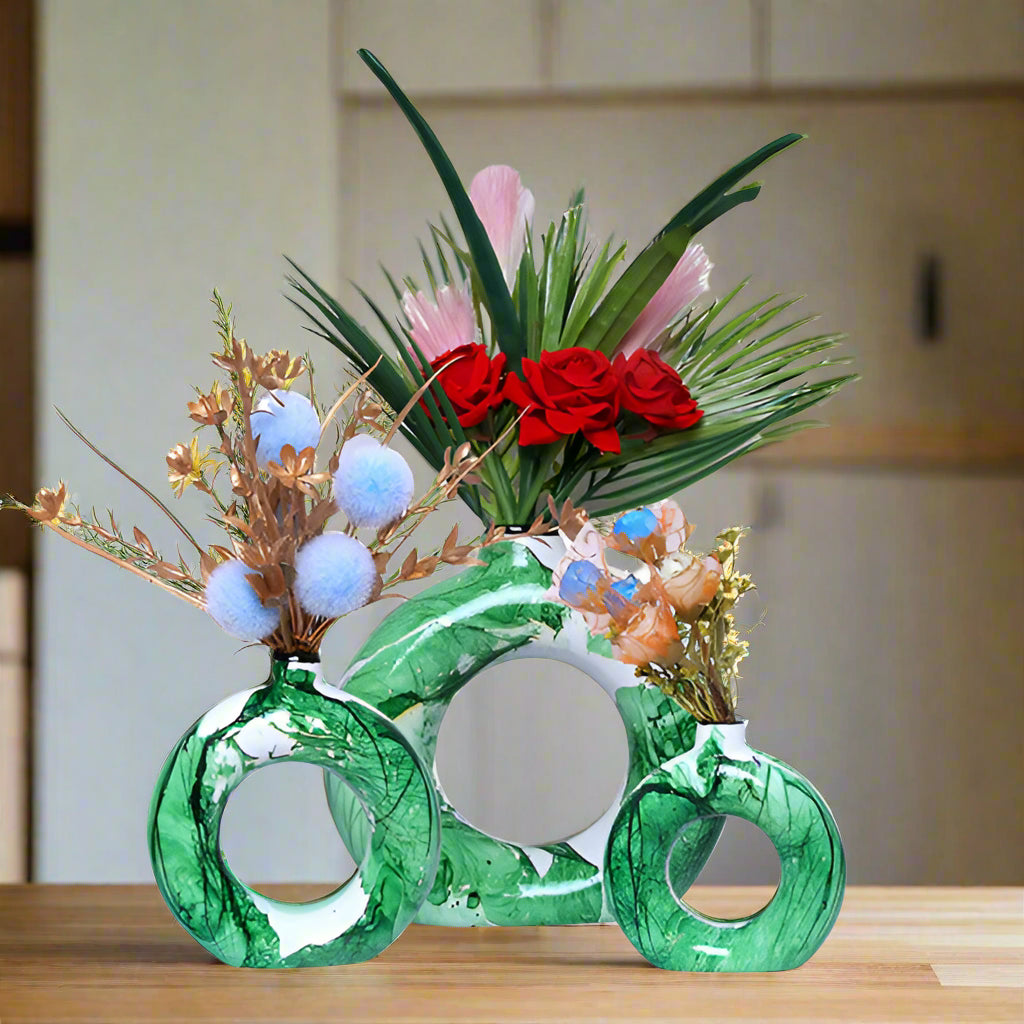 Green knuckle duster vase with floral arrangement on a white background